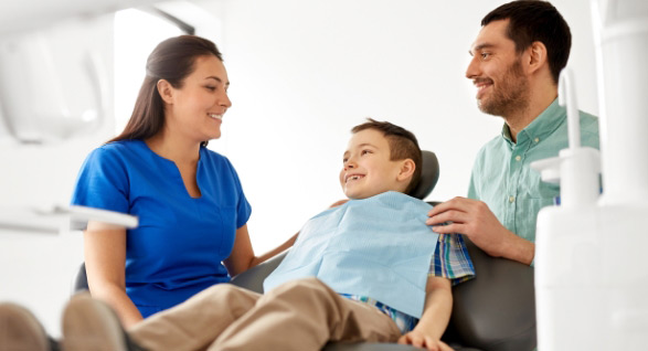 A mother, father, and their young child sitting together, smiling and sharing a happy moment as a family