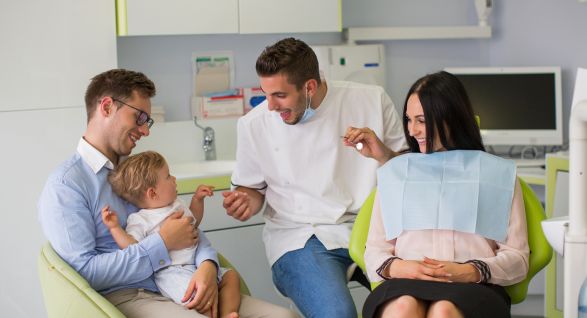 a dentist engaging with a young child and his parents in a pediatric and family dentistry office in Thunder Bay, Ontario.