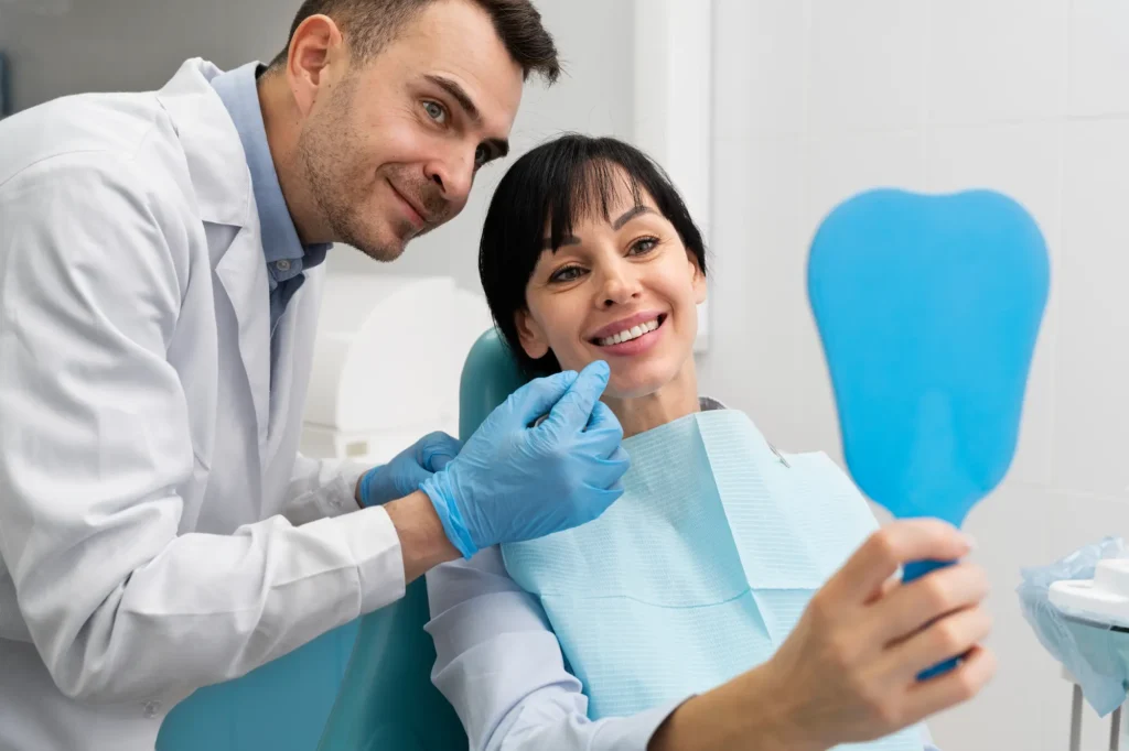 Dentist and assistant smiling with a female patient in a dental chair.