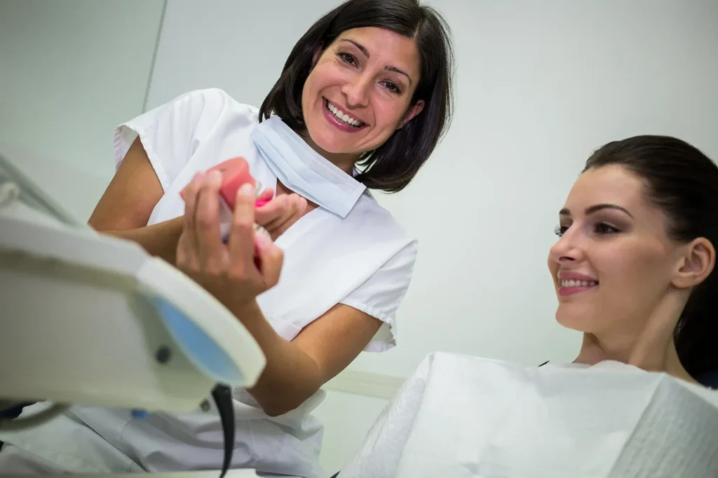Smiling female dentist holding a set of dental impressions in her office.
