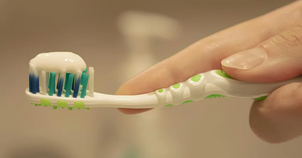 Hand holding a toothbrush with toothpaste ready for brushing as part of daily oral hygiene